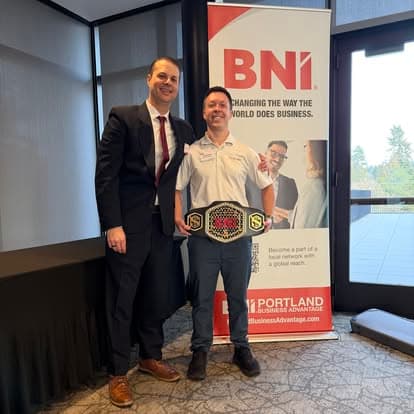 A member holding the chapter's championship belt next to a BNI banner